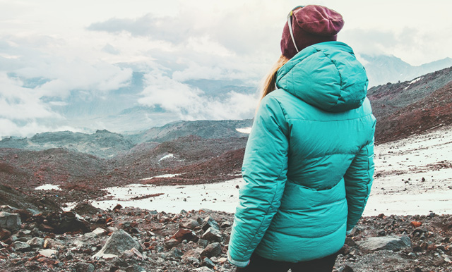 donna che indossa giacca invernale con cappuccio in montagna